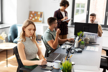 Fototapeta premium business, people and corporate concept - young woman with team of startuppers working at office