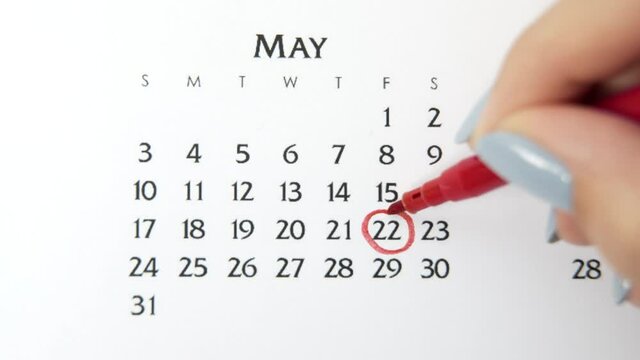 Female hand circle day in calendar date with a red marker. Business Basics Wall Calendar Planner and Organizer. May 22th
