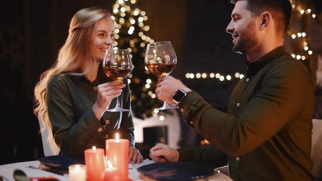 Drinking from big glasses. Sweet lovely couple having a romantic dinner indoors together.