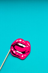 a stencil of beautiful female lips in a smile with a tongue with bright pink lipstick on a gentle blue plain background