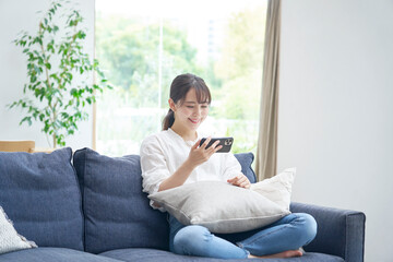 Obraz premium リビングでスマホを使う女性