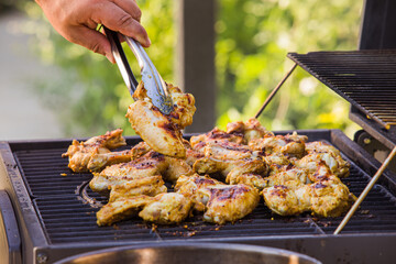 The man frying appetizing chicken wings on the grill