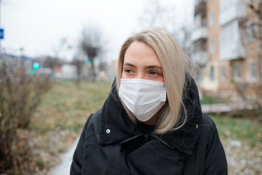 Young Woman In Medical Face Mask Outside. Portrait Of A Girl Looking To The Side In Winter