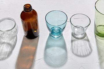 glassware concept - different glasses and bottles dropping shadows on white surface