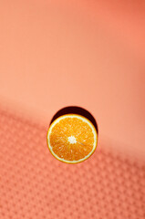 Top view of slice of orange on the bright orange background, decorative shadow