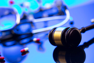 Obraz na płótnie Canvas Medical law concept. Gavel and stethoscope on the glass table. Blue light.