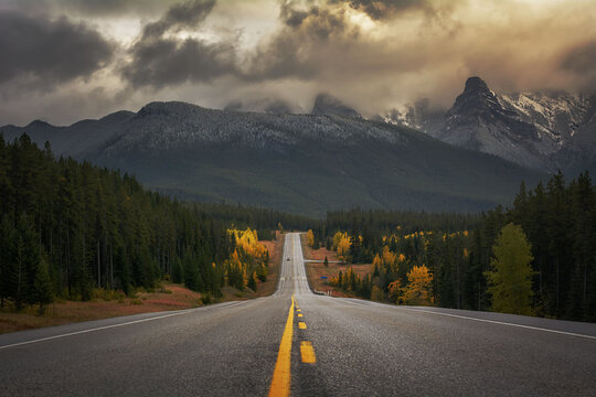 Diminishing Perspective Of Road Leading Towards Mountains Against Cloudy Sky