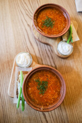 Ukrainian borscht with bacon bread sour cream and herbs on a wooden table in the dining room
