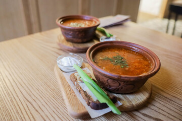 Ukrainian borscht with bacon bread sour cream and herbs on a wooden table in the dining room