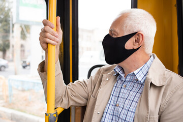 Senior man wearing medical face mask sitting in the bus transport.