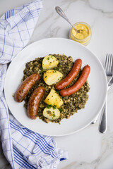 Oldenburger Grünkohl mit Pinkel, Kohlwurst, Senf und Kartoffeln auf Marmor Tisch