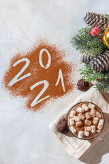 Cup of hot cocoa with marshmallows and numbers 2021 from cocoa powder. The concept of cosy holidays and New Year.