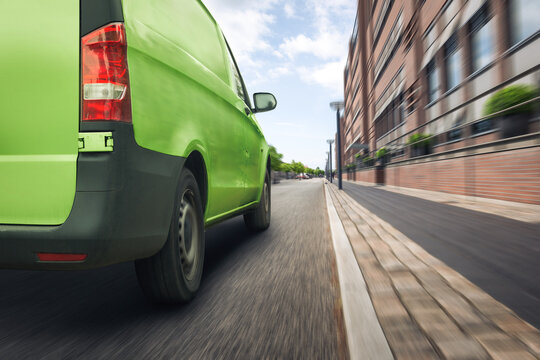 Green Delivery Van Driving On A Street In The City