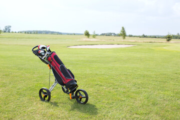 Fototapeta premium Golf club bag on pushcart at golf course against sky