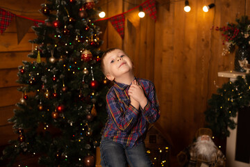 Portrait of happy boy sitting near Christmas tree. Merry Christmas and Happy New Year.