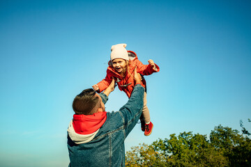 Flying high. Happy father and little cute daughter walking down the forest path in autumn sunny day. Family time, togehterness, parenting and happy childhood concept. Weekend with sincere emotions.