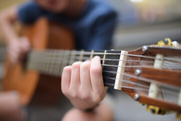 Fototapeta premium Young boy playing guitar outdoors