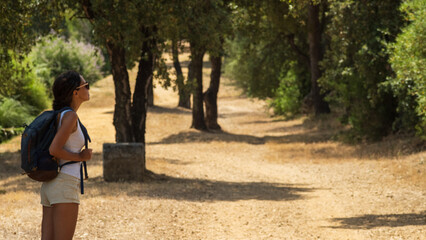 Backpack girl walking under trees in the summer