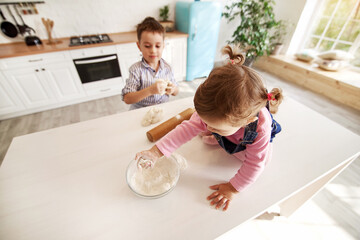 Kids in the kitchen playing with white flour