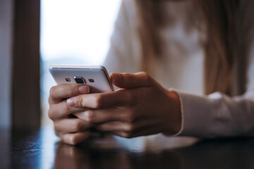 Female model holding in hands smartphone. Woman texting on the cellphone message