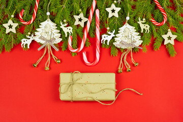 Christmas composition. Gifts, candy canes, christmas tree toys and spruce branches on a red background