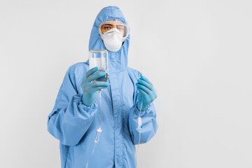 Doctor in a protective medical suit, mask, glasses and gloves, prepares a dropper for installation, on a white background, medical care concept, coronavirus