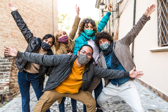 Happy Friends Walking On City Street - New Normal Concept With Young People Covered By Face Masks Having Fun Together 