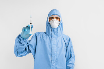 Male doctor in a protective medical suit, mask, glasses and gloves, with a syringe in his hands, the concept of medical care, coronavirus