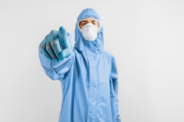 doctor dressed in a protective suit against coronavirus, wearing a medical mask, glasses and gloves, with his arms crossed on an white background. Quarantine, coronavirus
