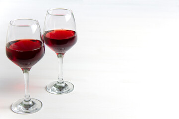 Two glasses of red wine on a white background and with a soft shadow. Side view. Copy space.