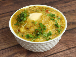Dal khichdi or Khichadi, Tasty Indian recipe served in bowl over rustic wooden background, The food made of dal and rice combined with whole spices, onions, garlic and tomatoes etc. Selective focus