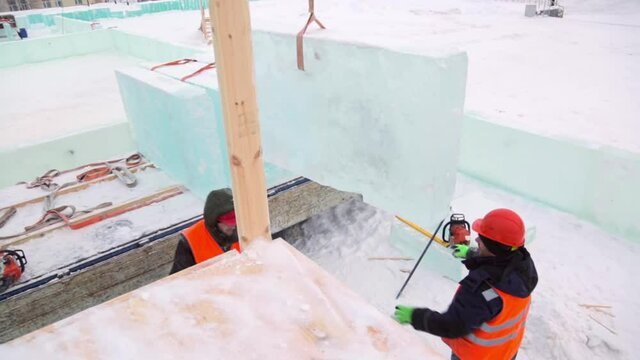 Installers in orange reflective vests and helmets on the installation of ice panels
