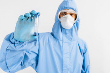 Male doctor in protective suit, medical protective mask, glasses and gloves, holding hourglass in hand, healthcare