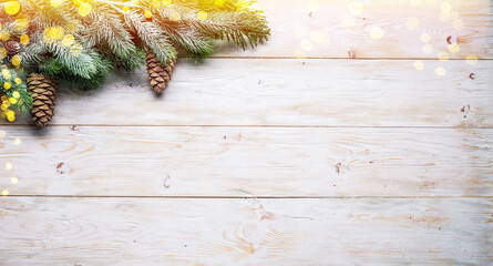 Snowy fir branch with fir cones on wooden table. Christmas or New Year holiday background.