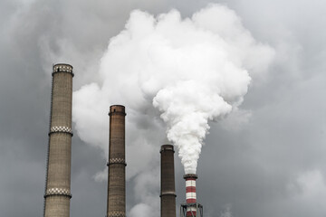 Smoking pipes of thermal power plant with dramatic dark cloudy sky