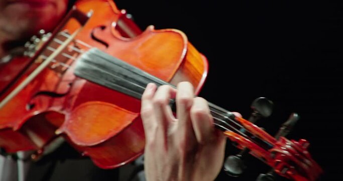 Close-up of a professional violinist playing the violin on a black background, 4k video.