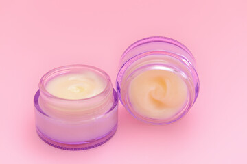 Cosmetic cream in glass jars on color background