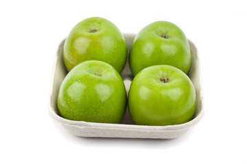 Four fresh green apples in a pulp paper tray. Studio photo isolated on white.