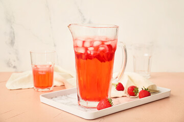 Jug of fresh strawberry lemonade on color table