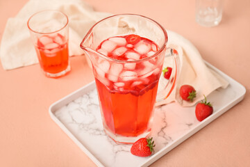 Jug of fresh strawberry lemonade on color table