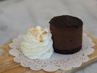 Chocolate Cake piece with Whipped Cream on white paper wooden tray
