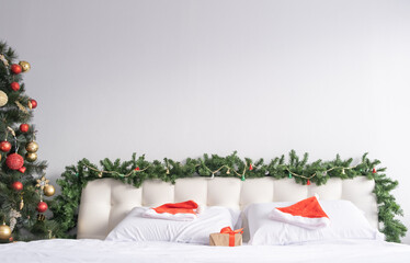 light bedroom with Christmas decorations. white bedding with Santa hats. copy space.