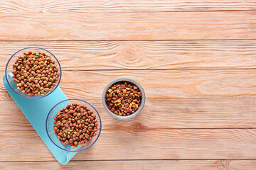 Bowls with dry pet food on wooden background
