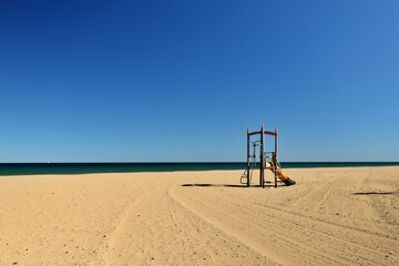 view of a lonely beach with a playground for children at mediterranean sea