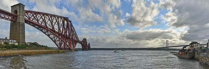 The original Forth Rail Bridge and the newer Forth Road Bridge stretch side by side from the harbor...