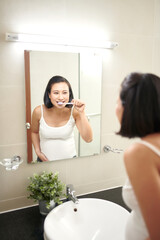 Portrait of beautiful pregnant woman brushing teeth at bathroom