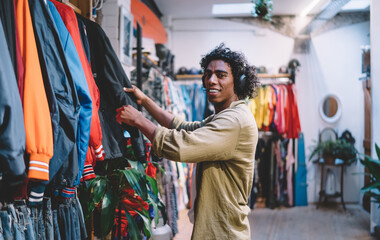 Positive young black man choosing clothes in store