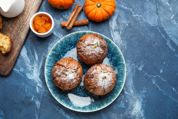 Plate with tasty pumpkin muffins on color background