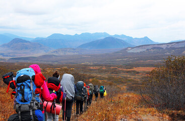 Active outdoors people lifestyle. 
A group of hikers with large tourist backpacks in the autumn mountains of Kamchatka. A difficult journey in the company of like-minded people and friends