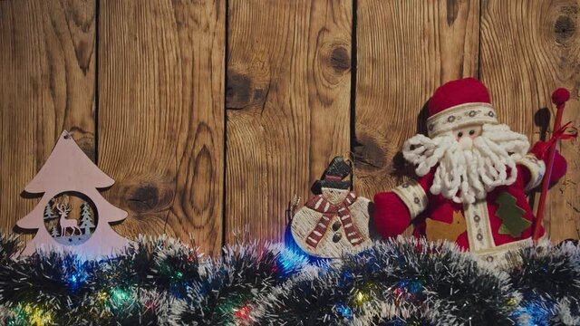 Christmas ornaments (Santa Claus, snowman and Christmas tree), tensil and garland on the background of a brushed wood with copy space. Christmas greeting card. 